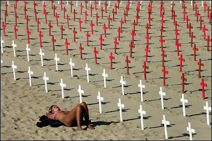 a woman in a bikini lying on a beach amongst rows of crosses