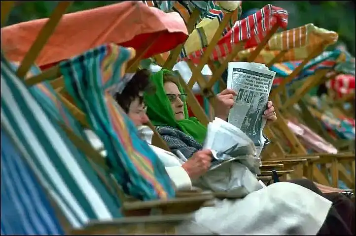 two women in deckchairs by the seaside on a cold day